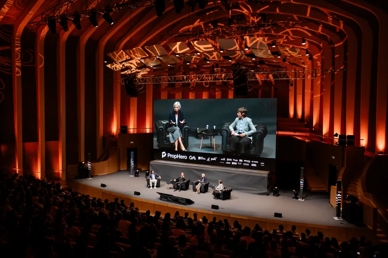 Panel sobre el escenario con otros ponentes en la pantalla gigante